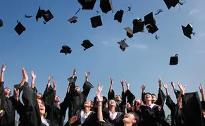 Image of school graduates throwing their graduation caps in the air