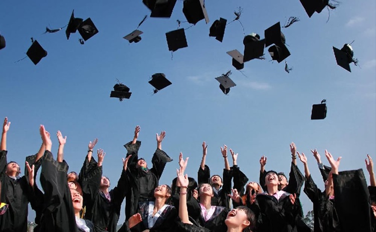 Image of school graduates throwing their graduation caps in the air