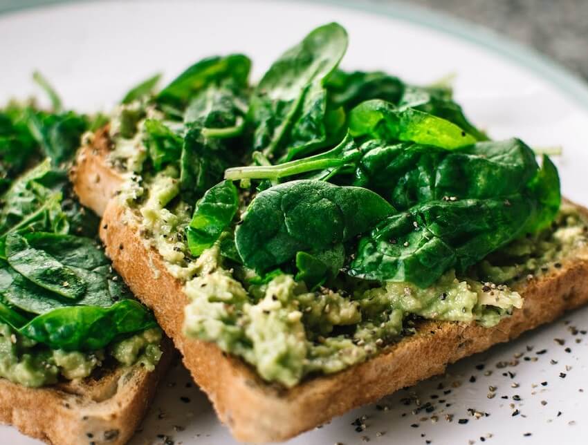 Wilted basil herbs on avocado toast