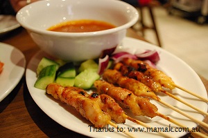 Chicken satay with a bowl of peanut sauce for dipping