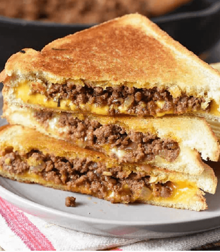 Stack of sloppy joe sandwiches with cheese which has been cooked like a grilled cheese sandwich